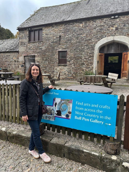 Joanna Williams standing next to a sign for the Bull Pen Gallery at National Trust Cotehele