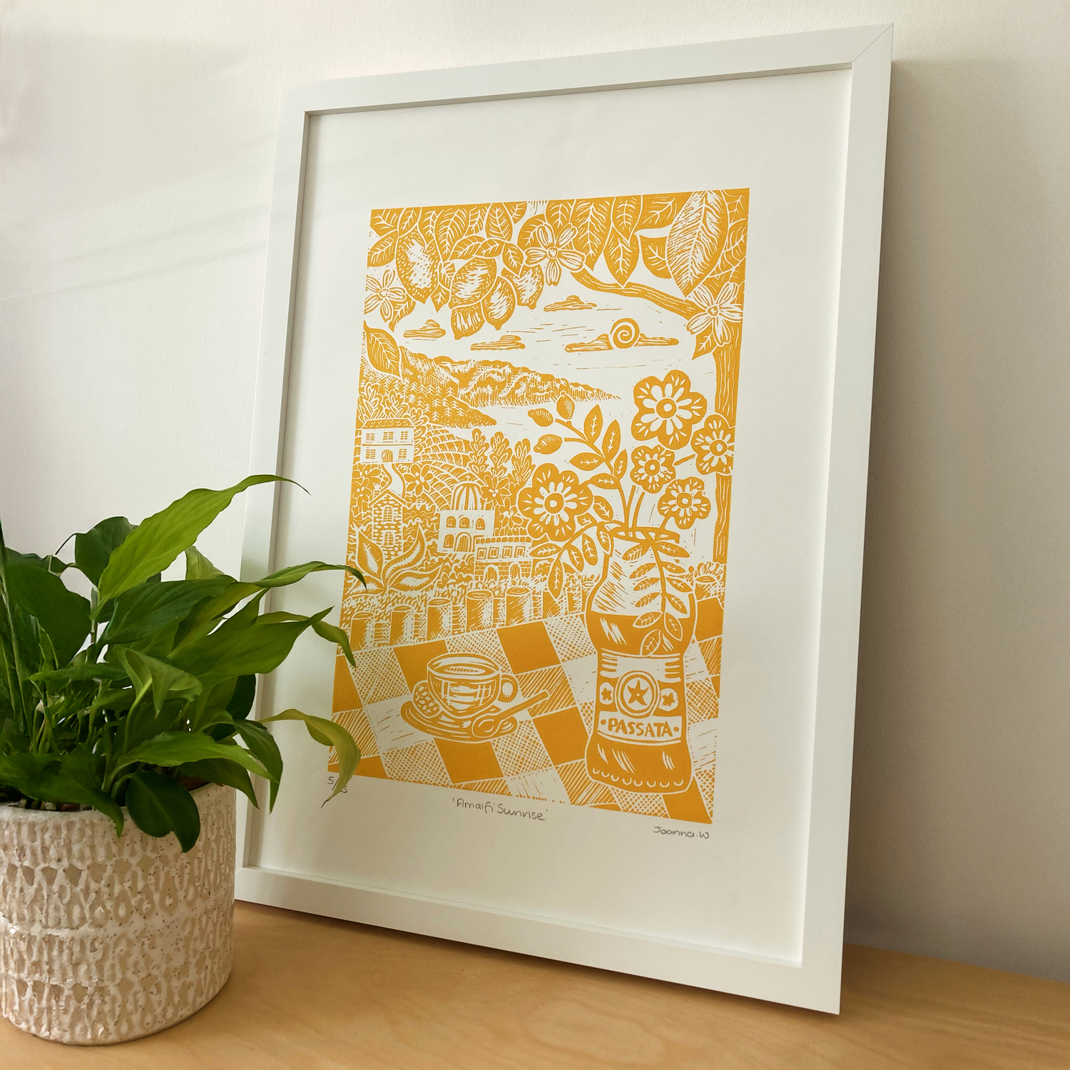 Joanna Williams Art Amalfi lino print in yellow next to a pot with a plant in