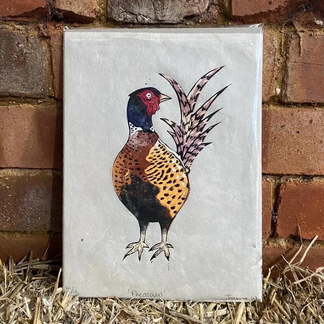 Framed illustration of a pheasant on a textured background with a brick wall and hay in the background by Joanna Williams Art - lino printer.
