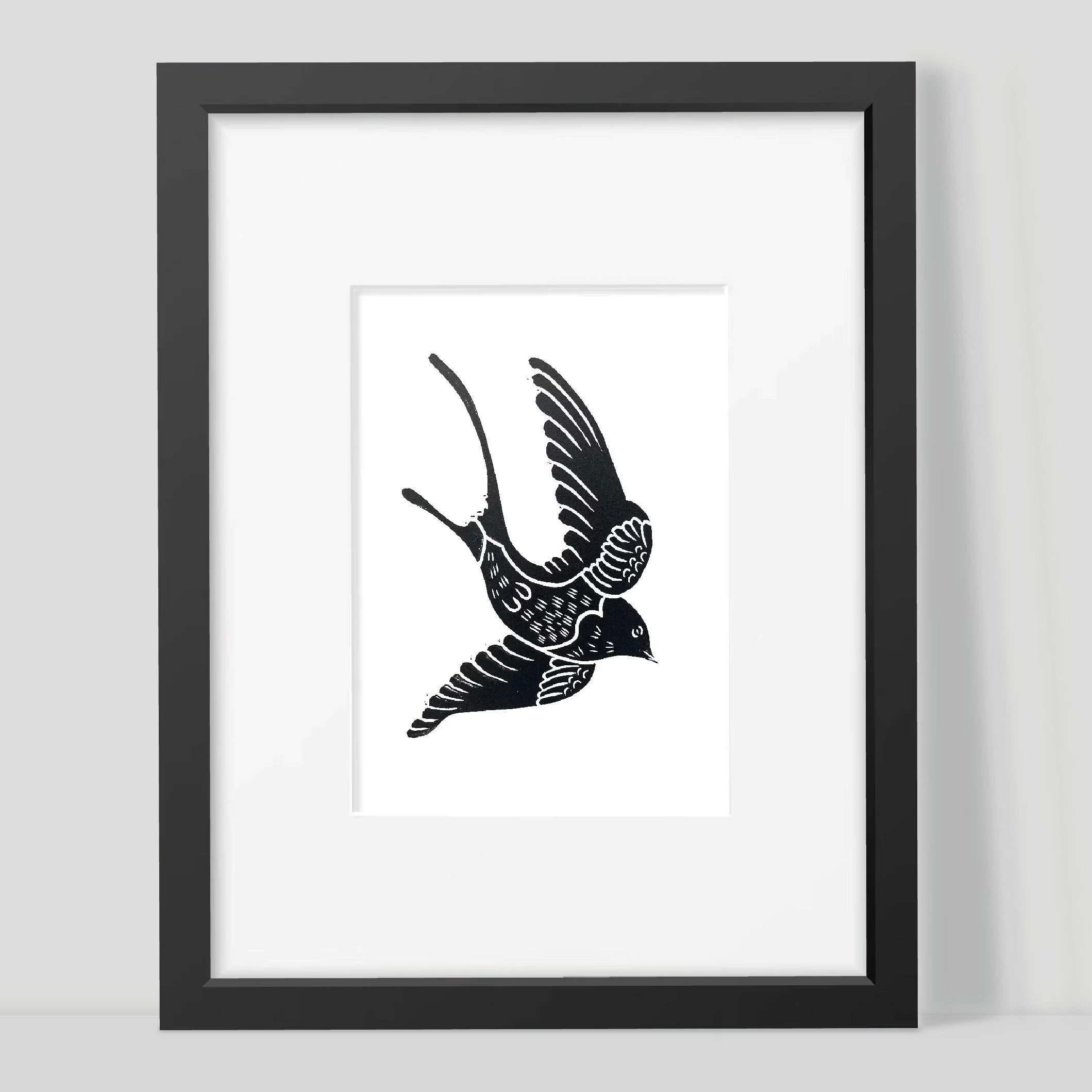 Framed artwork of a black swallow silhouette on a white background by Joanna Williams Art - lino printer.